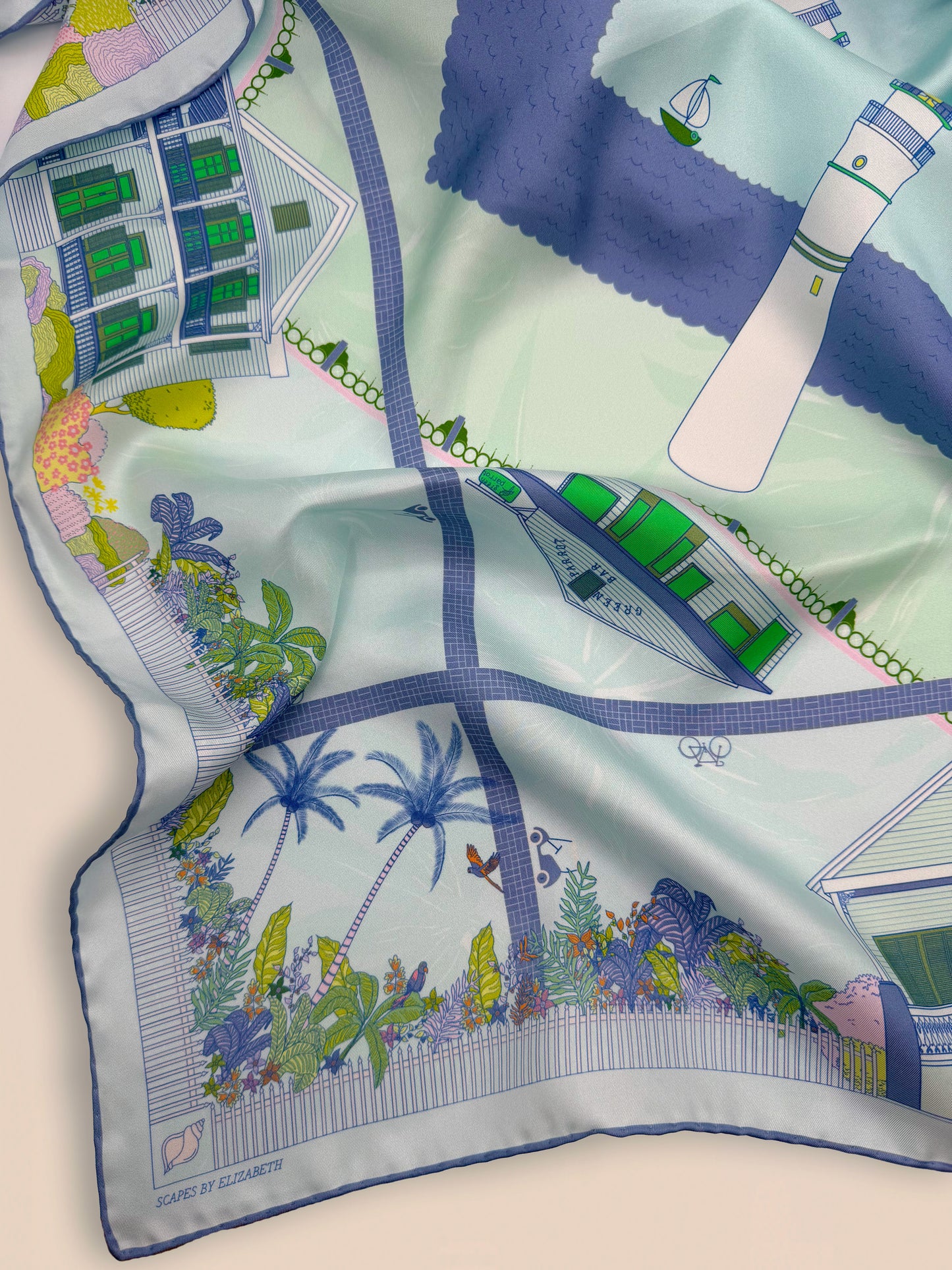 Close-up of the Seafoam Blue Key West silk scarf featuring hand-drawn Key West conch homes, ornate gingerbread houses, Duval Street buildings, conch shells, coastal views, palm trees, lush tropical landscaping, and the Key West Lighthouse.
