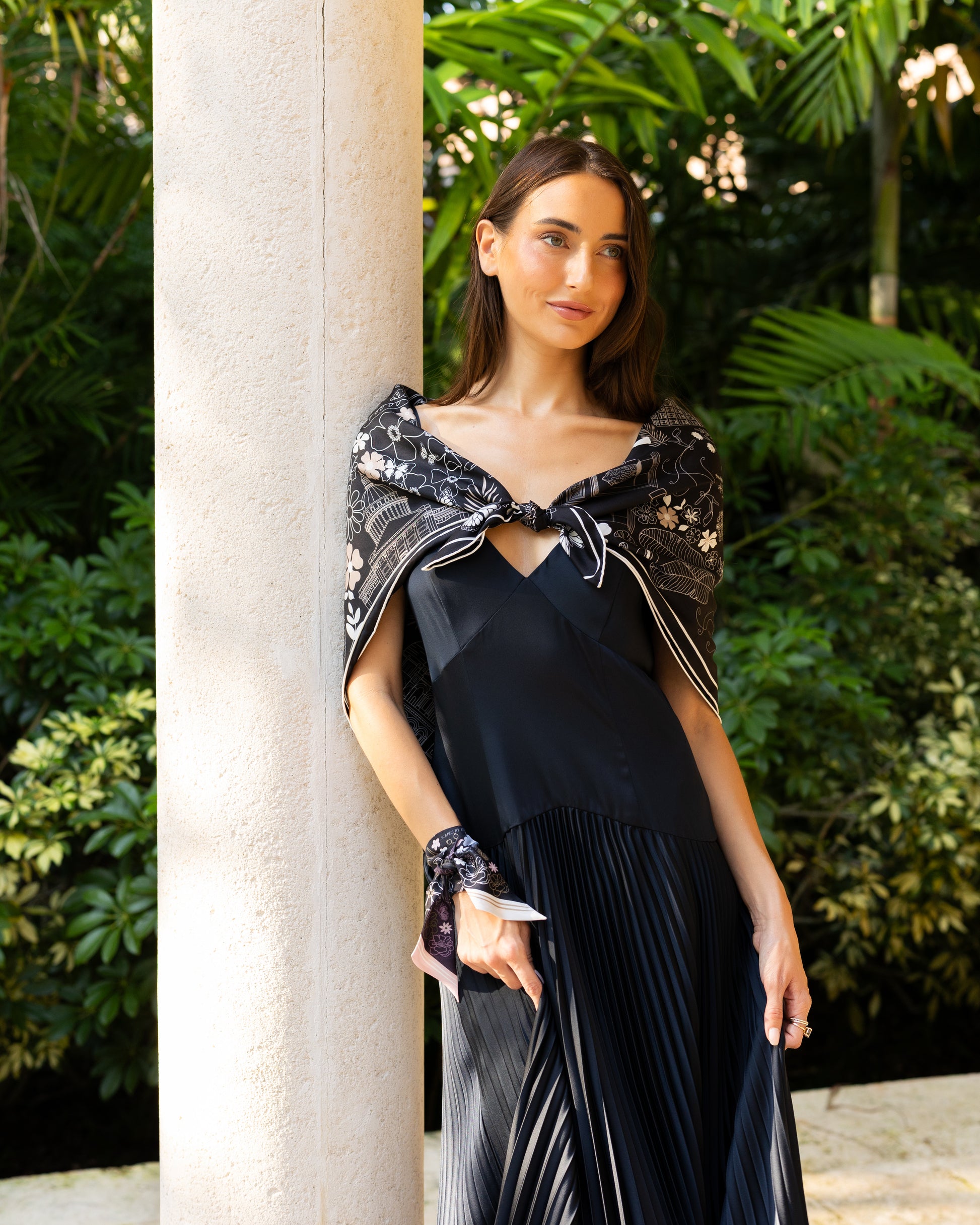 Woman wearing a black and white Paris silk scarf featuring hand-drawn Paris landmarks as an elegant shawl with an evening dress.