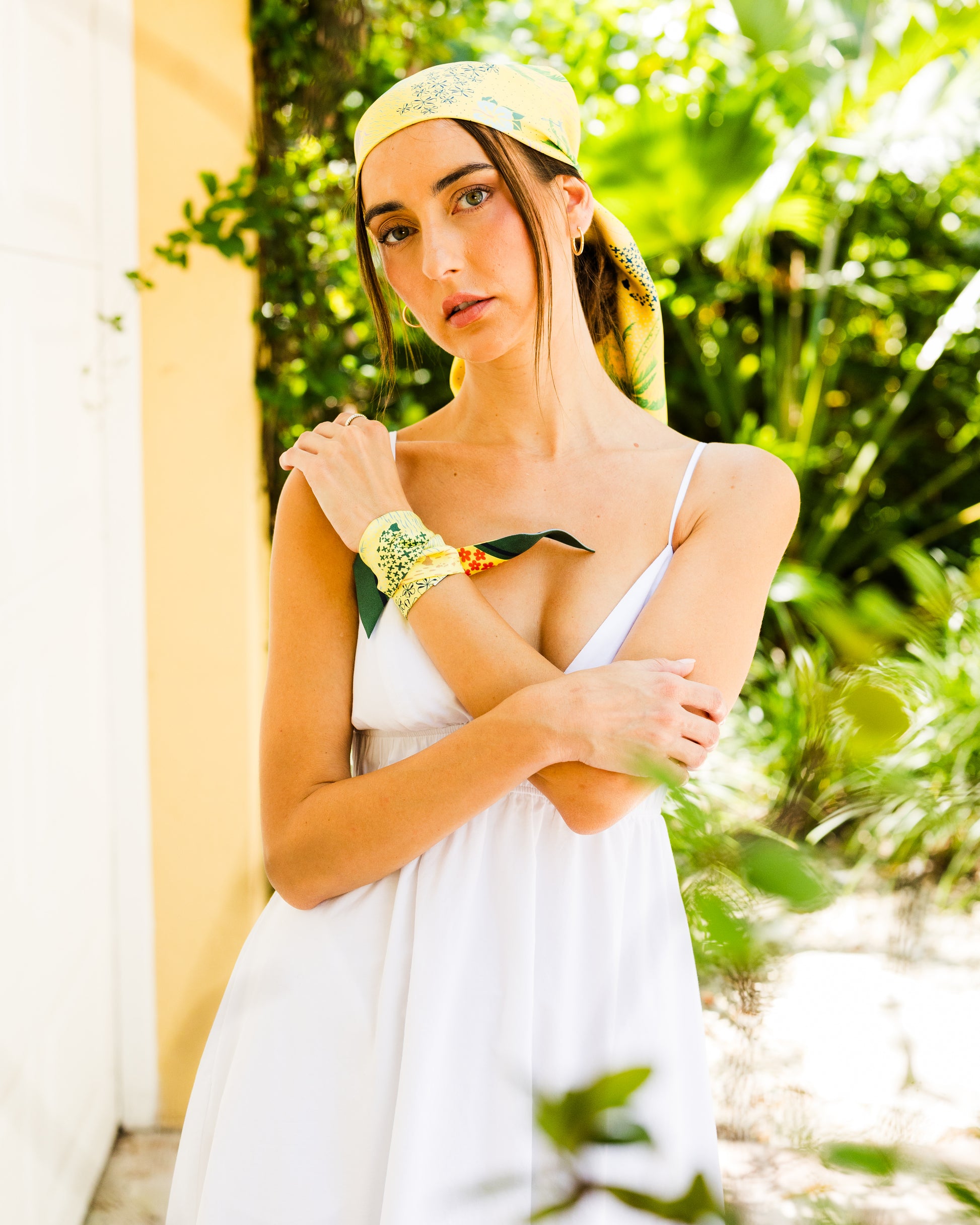 Woman wearing the Pineapple Yellow Hawaii silk twilly as a bracelet with the matching Hawaii silk scarf styled as a head scarf, featuring colorful hand-drawn tropical and island-inspired artwork.