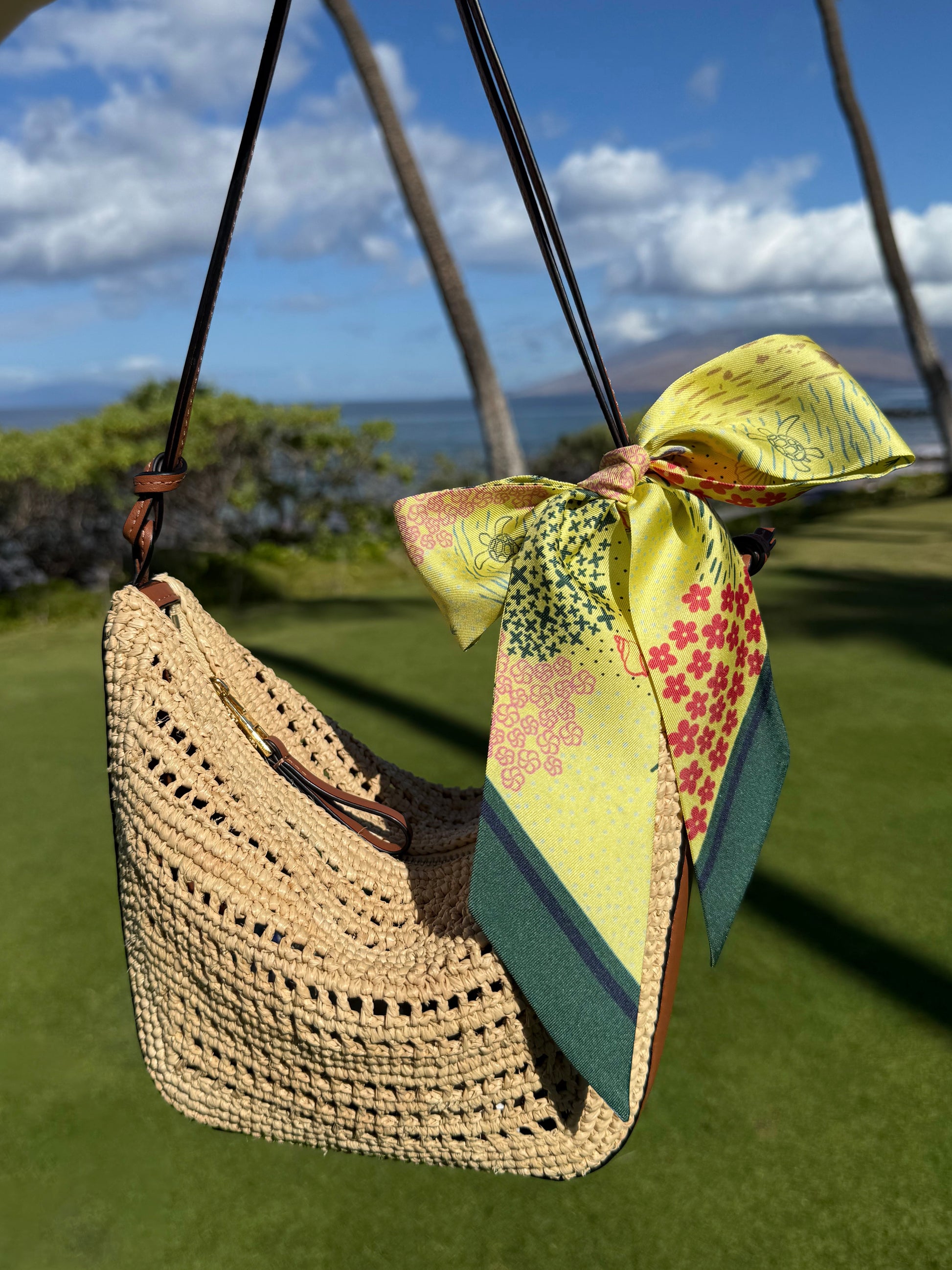 Pineapple Yellow Hawaii silk twilly featuring vibrant Hawaiian-inspired artwork tied in a bow on a raffia handbag for a tropical summer look.