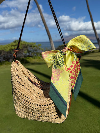 Pineapple Yellow Hawaii silk twilly featuring vibrant Hawaiian-inspired artwork tied in a bow on a raffia handbag for a tropical summer look.