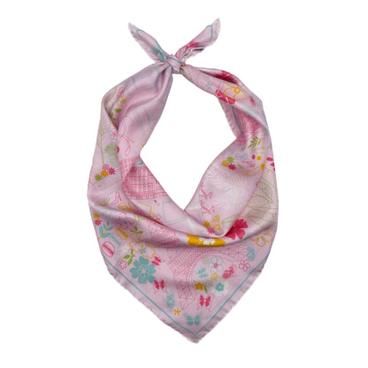 Rose Allure Paris silk scarf tied into a bandana featuring a hand-drawn map of Paris with the Eiffel Tower, Arc de Triomphe, Moulin Rouge, and colorful Paris-inspired artwork on a light pink background.