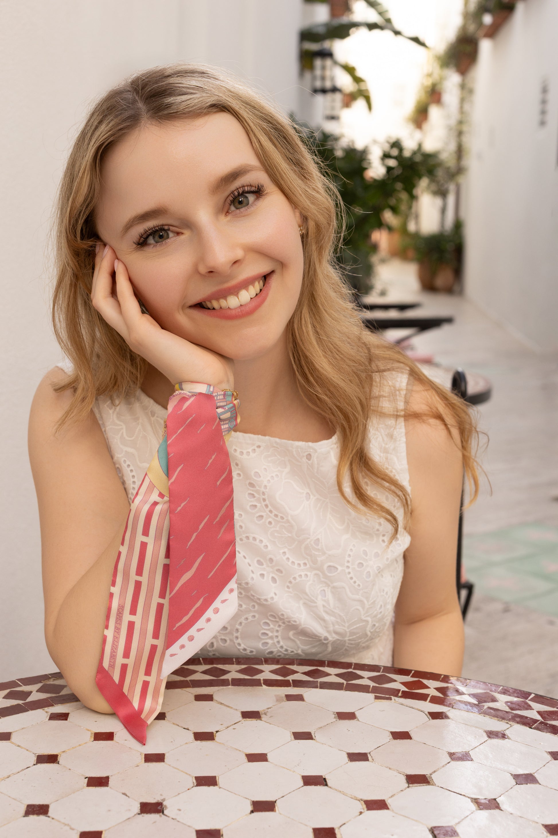 Woman wearing the Rosy Splash Miami Beach silk twilly as a bracelet featuring hand-drawn Art Deco buildings and coastal-inspired artwork in bright Miami-inspired colors.