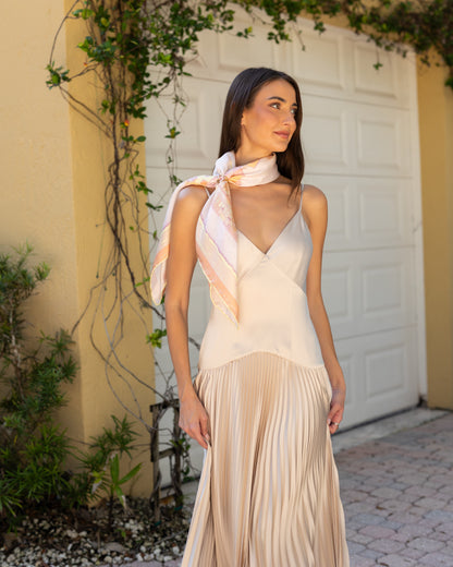 Woman wearing the Sunset Miami Beach silk scarf draped around her neck with a scarf ring and a gold evening dress, featuring hand-drawn miami Art Deco architecture, lifeguard towers, palm trees, and coastal-inspired artwork.